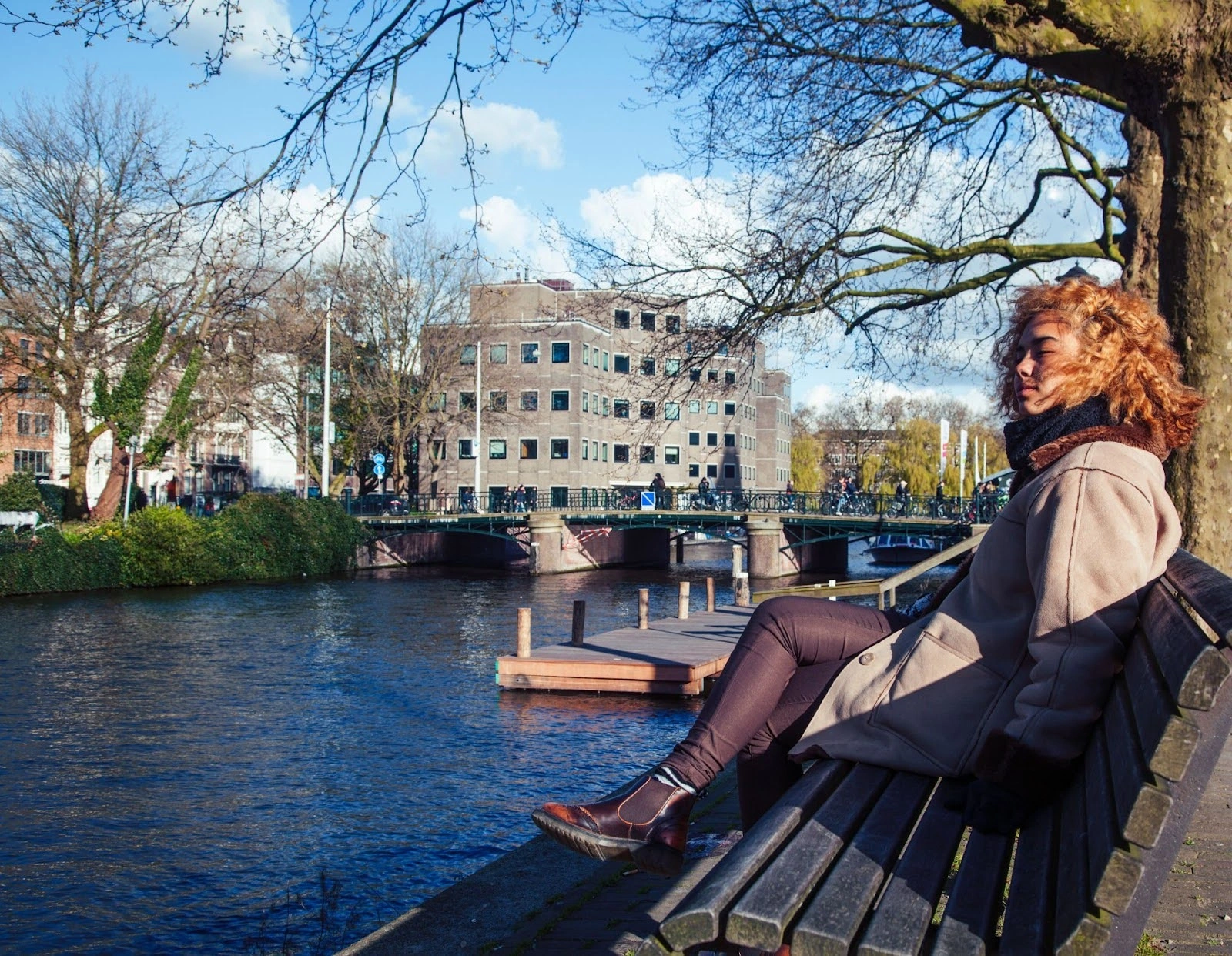 Vrouw zit op bankje langs Amsterdamse gracht in rustig moment